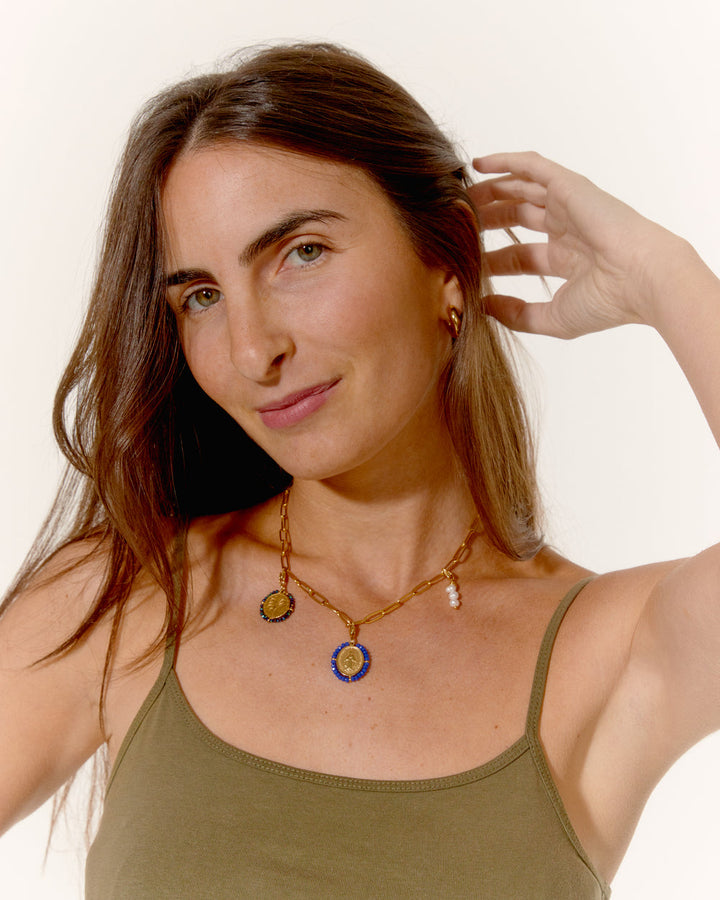 Woman wearing a necklace with multiple pendants on a plain background