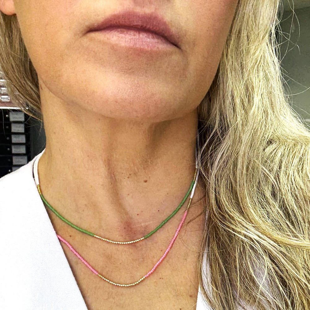 Close-up of a person wearing two necklaces with a blurred background