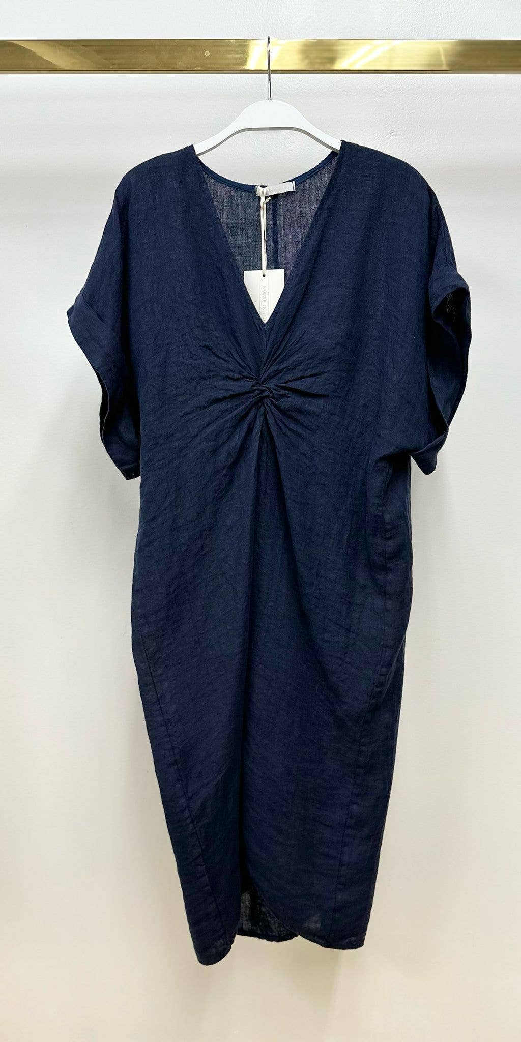 Navy blue dress on a hanger against a white background